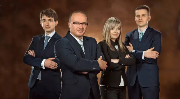 Zespół prawników w garniturach pozuje na brązowym tle.