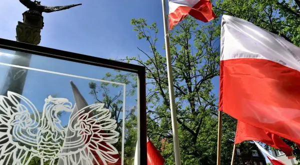 Orzeł biały i polskie flagi na tle nieba. Czy 3 maja można pracować? To pytanie zadają sobie Polacy w święto Konstytucji.