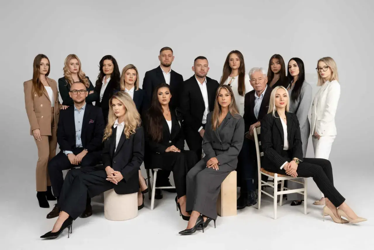 Grupa prawników i radców prawnych w eleganckich strojach pozuje do zdjęcia.