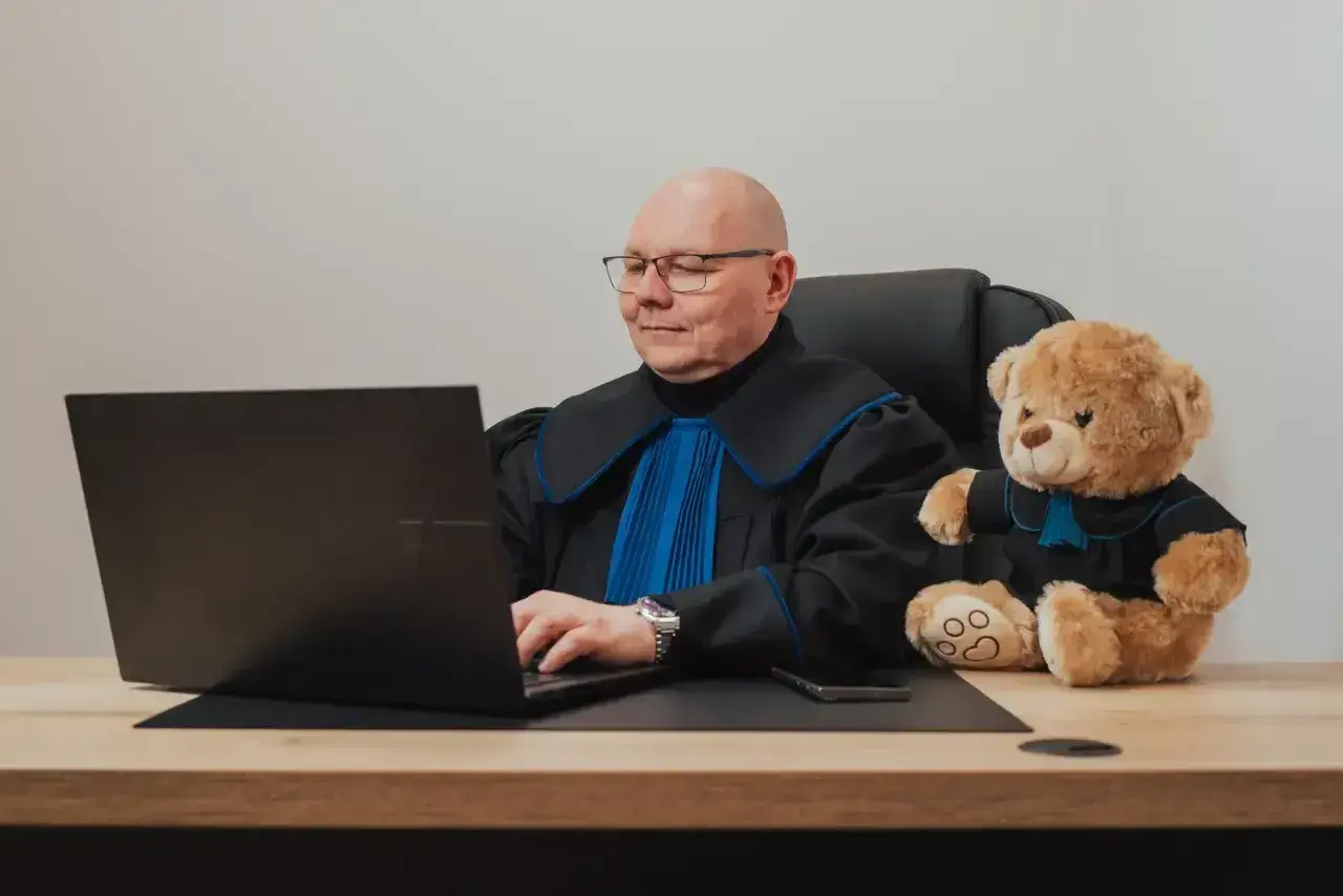Sędzia z pluszowym misiem przy laptopie. Zastanawiasz się, ile kosztuje porada prawna u notariusza?