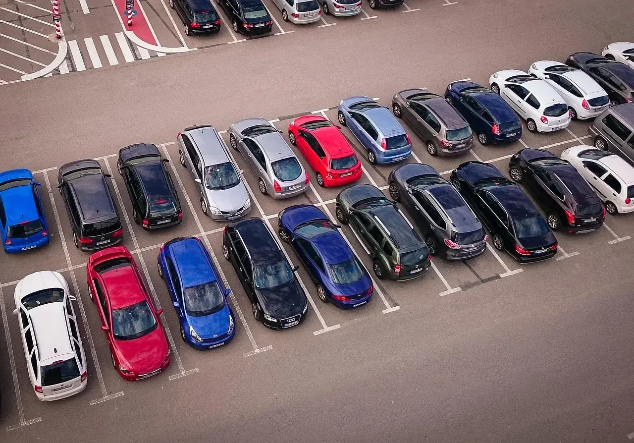 Wiele samochodów na parkingu, zastanawiasz się, czy wybrać prawne rozwiązania parkingowe czy płacić za postój.