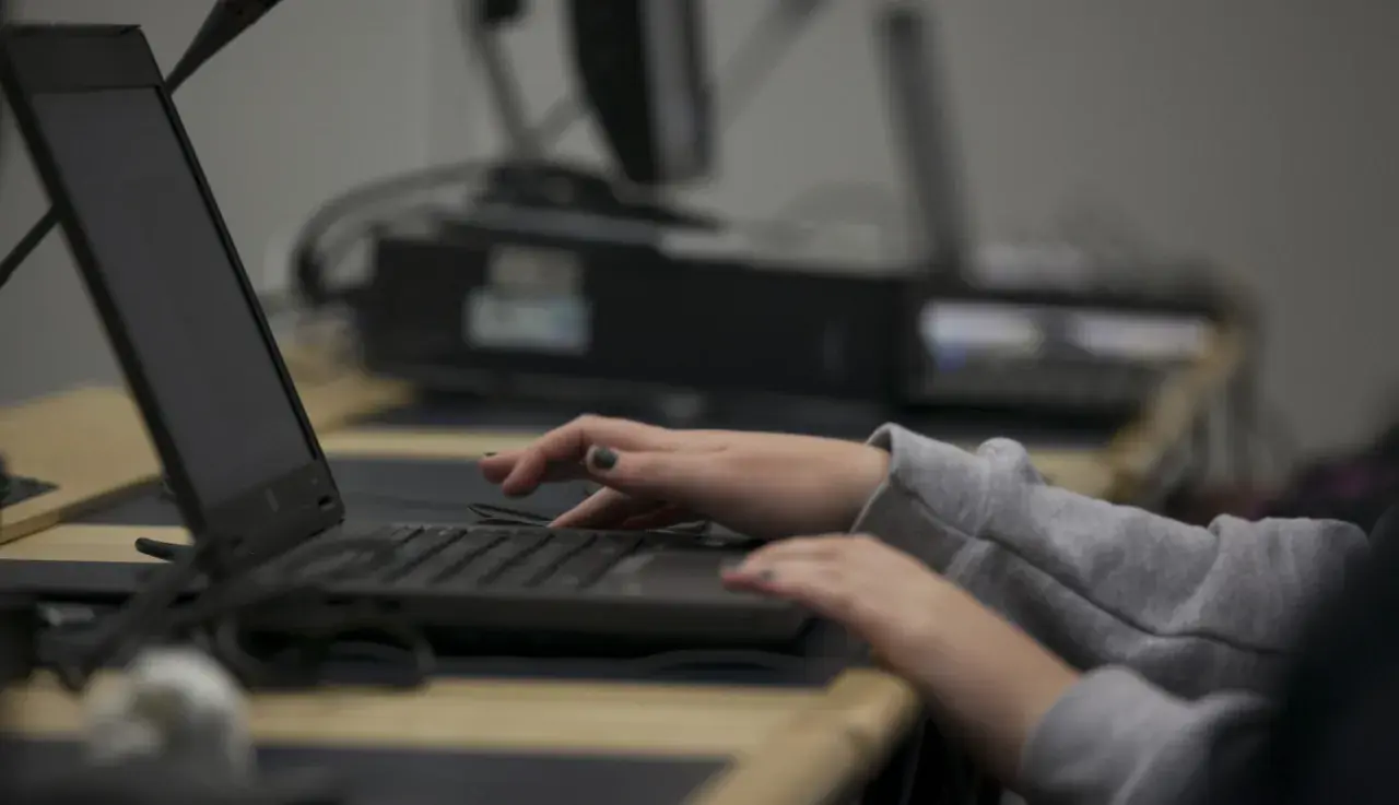 Dłonie piszą na klawiaturze laptopa, jakby w pośpiechu, jakby ktoś prowadził **stalking** w sieci.