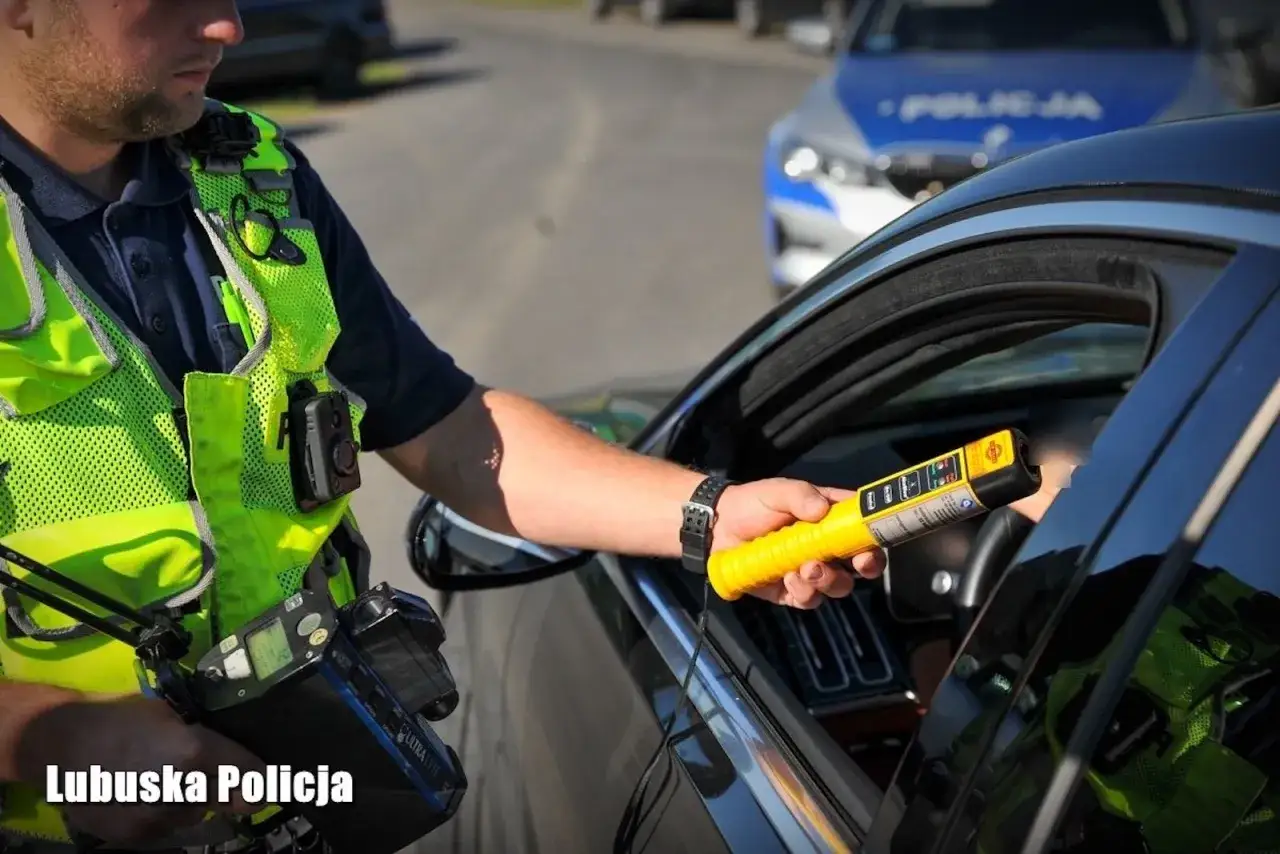 Policjant z Lubuskiej Policji bada kierowcę alkomatem. To kontrola trzeźwości, by zapobiec jeździe pod wpływem.
