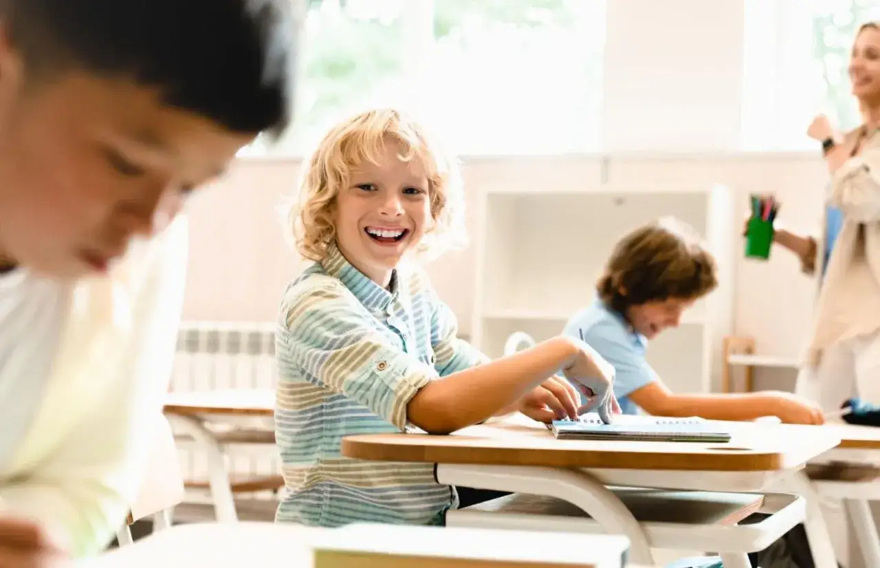 Uśmiechnięty chłopiec na lekcji, radość z edukacji wczesnoszkolnej.