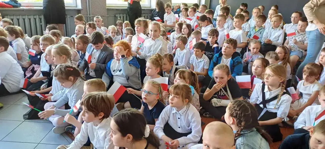 Dzieci z polskimi flagami, gotowe do lekcji. Obowiązek szkolny to ważny etap w życiu każdego młodego Polaka.