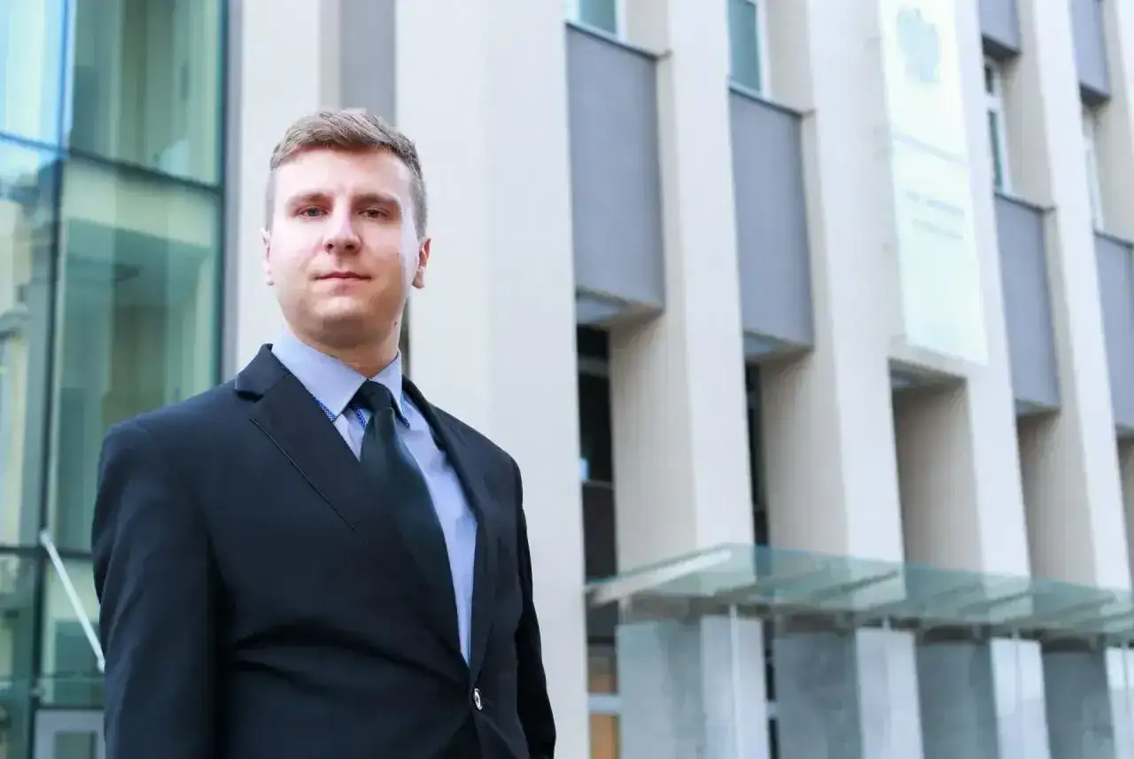 Mężczyzna w garniturze przed nowoczesnym budynkiem.