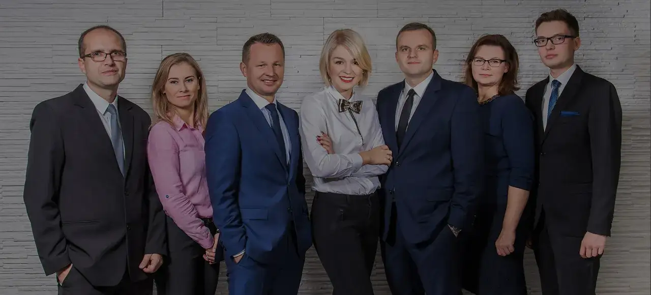 Grupa prawników i adwokatów w garniturach i eleganckich strojach pozuje do zdjęcia.