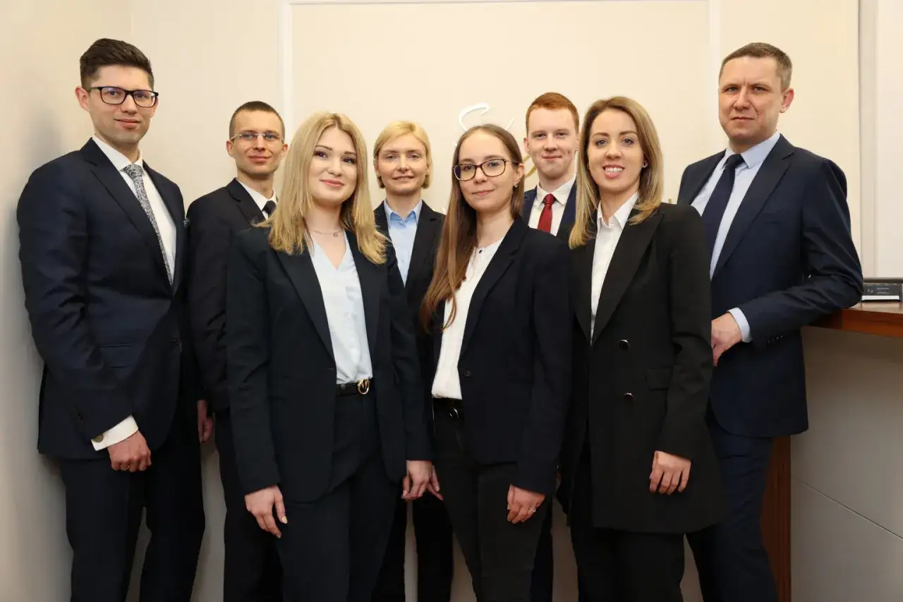 Grupa prawników w garniturach pozuje do zdjęcia.