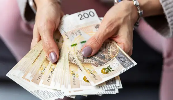 Dłonie trzymają stos banknotów 200 zł. Czy to zapowiedź sankcji kredytu darmowego?