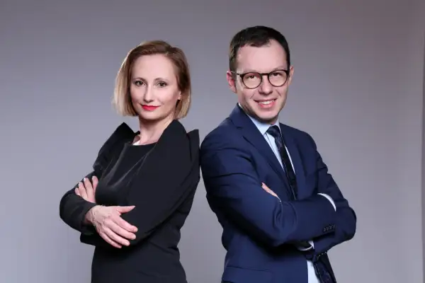 Kobieta i mężczyzna w strojach biznesowych stoją plecami do siebie, patrząc w stronę widza.