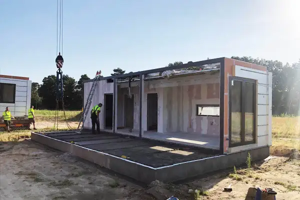 Budowa modułowego budynku, zgodna z art. 29 prawa budowlanego. Dźwig podnosi element konstrukcyjny.