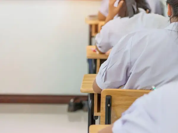 Uczniowie w białych koszulach siedzą w ławkach, skupieni na zadaniach. Może to być dzień, w którym marzą o zwolnieniu z egzaminu ósmoklasisty.