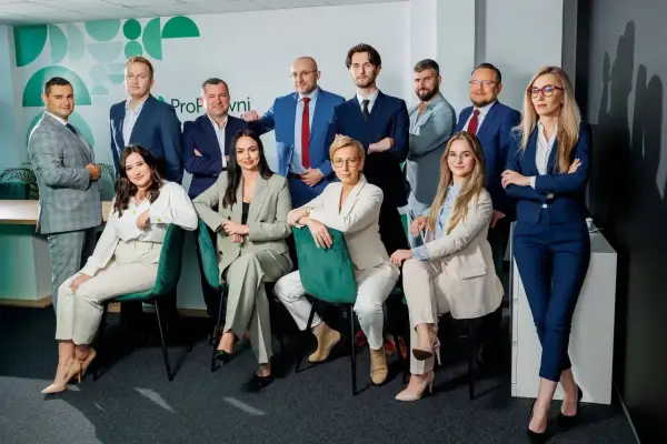 Zespół prawników w garniturach pozuje do zdjęcia w nowoczesnym biurze.