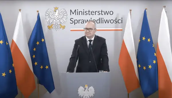 Minister sprawiedliwości przemawia na tle flag Polski i UE. Tematem dyskusji jest ustawa frankowa.