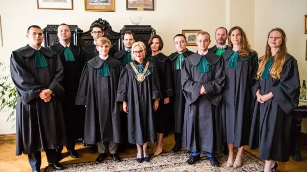 Grupa prawników w togach stoi w pomieszczeniu.