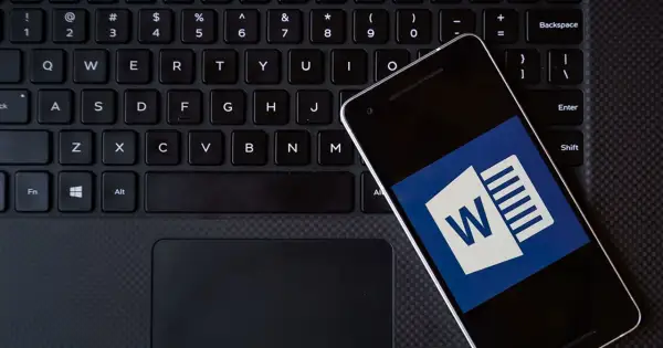 Smartfon z ikoną Worda leży na klawiaturze. Możesz kliknąć ten hiperłącze, aby otworzyć dokument.